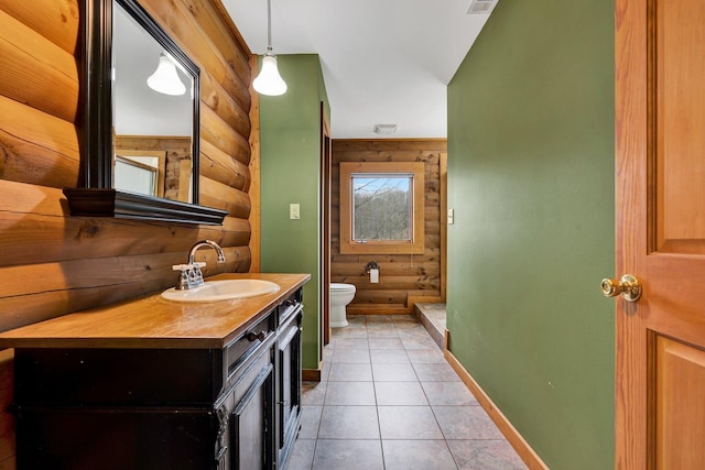 bathroom with a shower, rustic walls, tile patterned flooring, vanity, and toilet