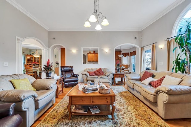 living room with an inviting chandelier, ornamental molding, light hardwood / wood-style floors, and ornate columns