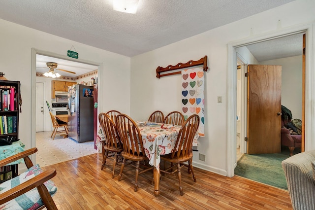 dining space with ceiling fan, light hardwood / wood-style floors, and a textured ceiling