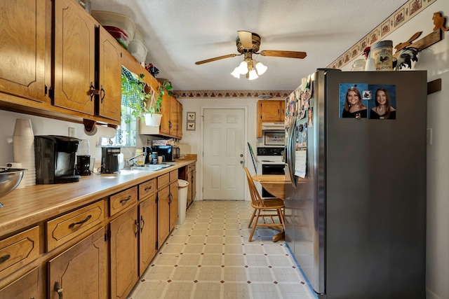 kitchen featuring stainless steel refrigerator with ice dispenser, ceiling fan, electric stove, and sink