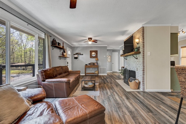 living room featuring crown molding, a textured ceiling, ceiling fan, a fireplace, and hardwood / wood-style floors