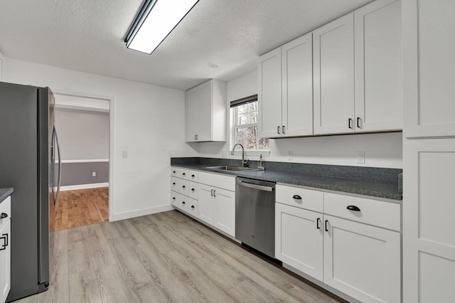 kitchen featuring stainless steel appliances, white cabinetry, sink, and a textured ceiling