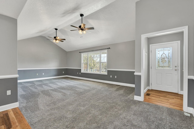 entryway featuring ceiling fan, lofted ceiling, carpet flooring, and a textured ceiling