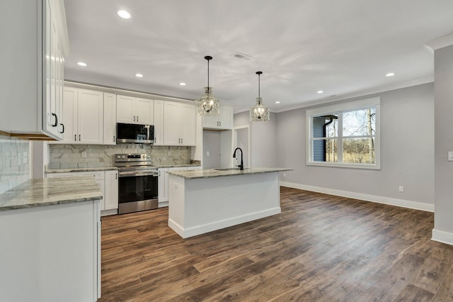 kitchen with pendant lighting, appliances with stainless steel finishes, a kitchen island with sink, and white cabinets