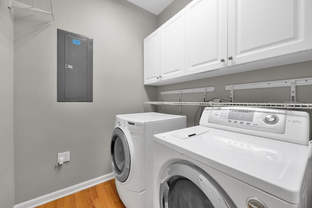 washroom featuring cabinets, separate washer and dryer, electric panel, and light hardwood / wood-style flooring