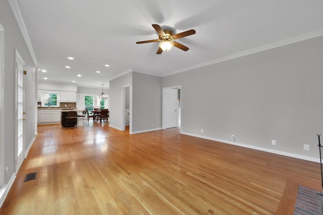 unfurnished living room featuring crown molding, ceiling fan with notable chandelier, and light wood-type flooring