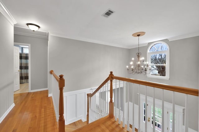 corridor with crown molding, a chandelier, and light hardwood / wood-style flooring