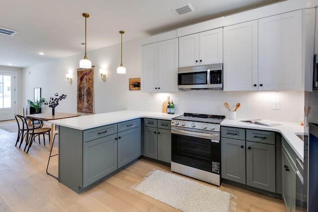 kitchen with light hardwood / wood-style flooring, appliances with stainless steel finishes, hanging light fixtures, white cabinets, and kitchen peninsula