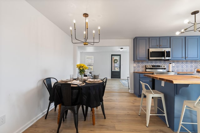 interior space with appliances with stainless steel finishes, decorative light fixtures, butcher block counters, a chandelier, and decorative backsplash