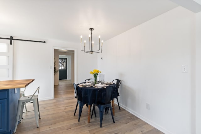 dining area featuring a barn door, a chandelier, and light hardwood / wood-style flooring