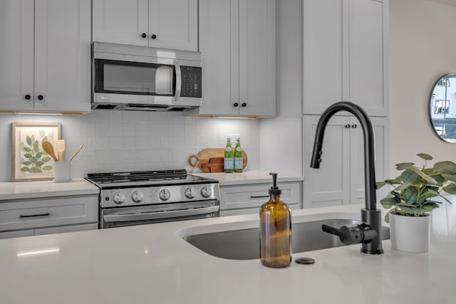 kitchen featuring stainless steel appliances, sink, decorative backsplash, and white cabinets