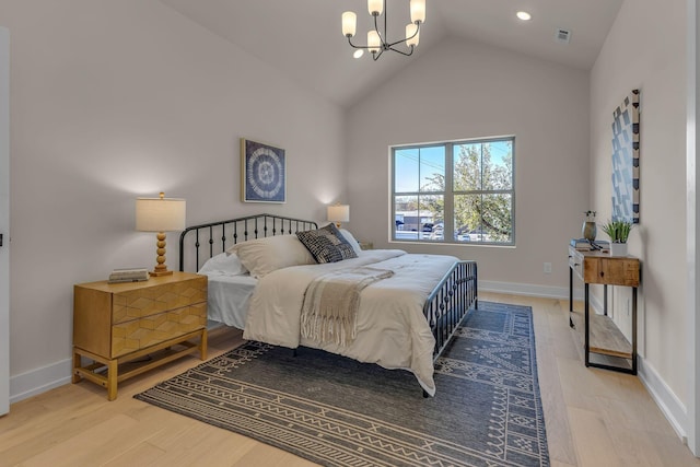 bedroom featuring an inviting chandelier, high vaulted ceiling, and light hardwood / wood-style flooring