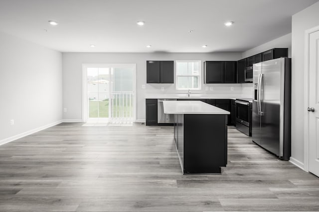 kitchen with stainless steel appliances, a center island, sink, and light hardwood / wood-style floors