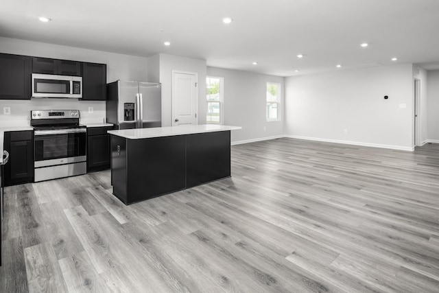 kitchen with light hardwood / wood-style flooring, stainless steel appliances, and a center island