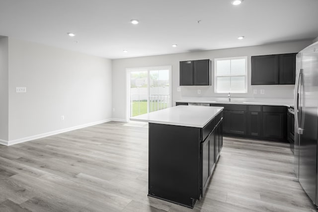 kitchen with light hardwood / wood-style flooring, sink, stainless steel fridge, and a kitchen island