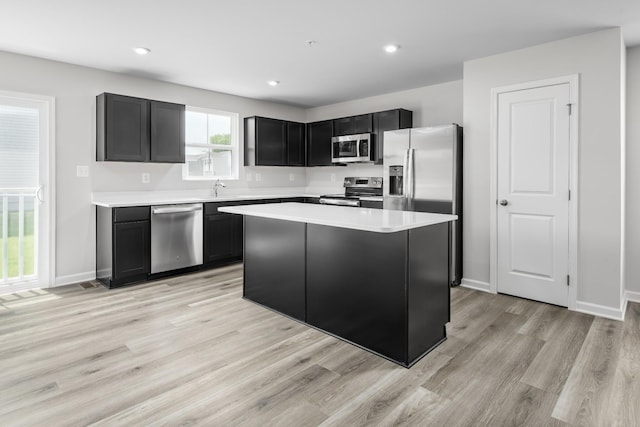 kitchen featuring appliances with stainless steel finishes, sink, a kitchen island, and light wood-type flooring