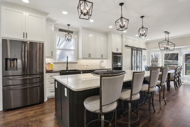 kitchen with white cabinetry, hanging light fixtures, stainless steel appliances, and a center island