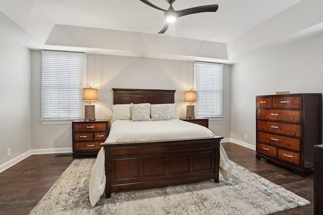 bedroom featuring dark hardwood / wood-style floors, ceiling fan, and a tray ceiling