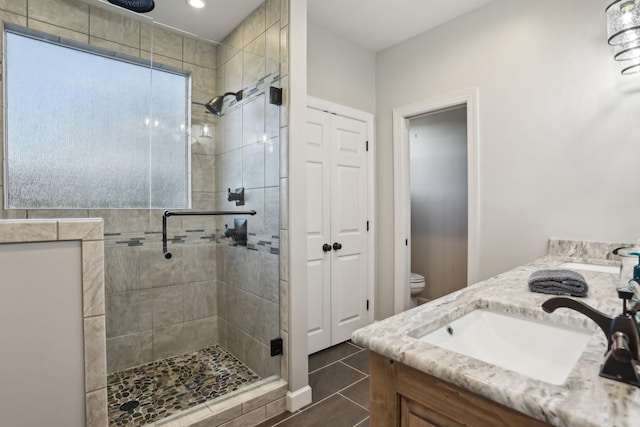 bathroom featuring a shower with door, vanity, tile patterned floors, and toilet