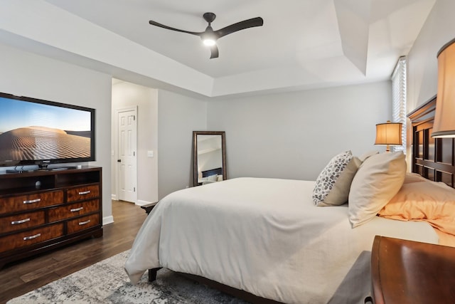 bedroom featuring a tray ceiling, dark hardwood / wood-style floors, and ceiling fan