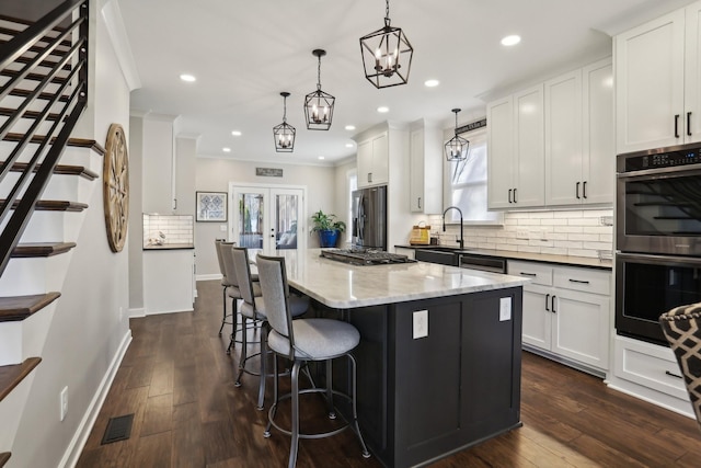 kitchen with appliances with stainless steel finishes, pendant lighting, sink, white cabinets, and dark stone counters