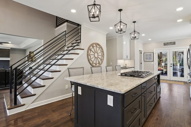 kitchen featuring french doors, hanging light fixtures, dark hardwood / wood-style flooring, a kitchen island, and stainless steel gas stovetop