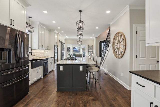 kitchen with decorative light fixtures, a kitchen island, white cabinets, and appliances with stainless steel finishes