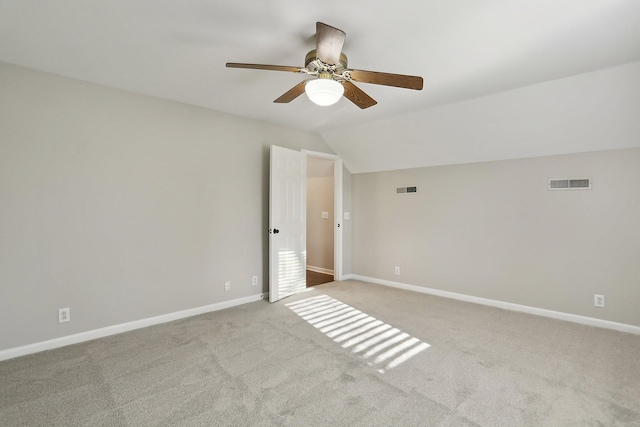 spare room with ceiling fan, light colored carpet, and vaulted ceiling