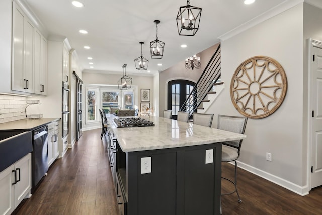 kitchen with a breakfast bar area, white cabinetry, decorative light fixtures, a center island, and stainless steel appliances