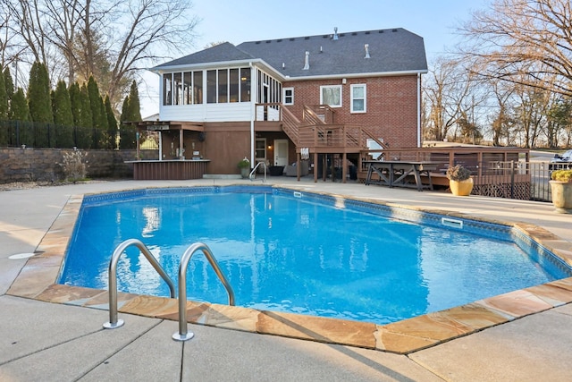 view of pool featuring a wooden deck, a patio area, and a sunroom