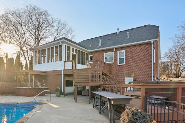 back of house featuring a swimming pool with hot tub, a patio, and a sunroom