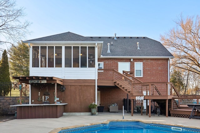 rear view of property with a pool side deck, a sunroom, and a patio