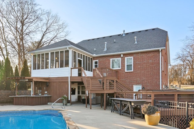 rear view of property featuring a pool side deck, a patio area, and a sunroom