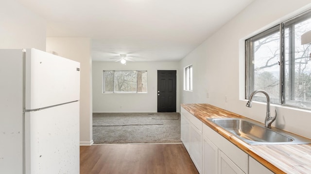 kitchen featuring wood counters, sink, white cabinets, white fridge, and ceiling fan