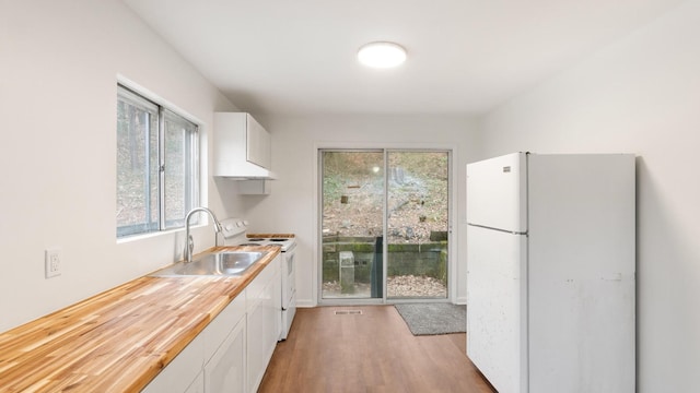 kitchen featuring sink, white cabinets, white appliances, and light wood-type flooring