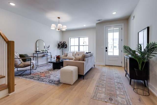 living room featuring plenty of natural light, light hardwood / wood-style floors, and a notable chandelier