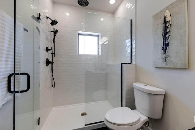 bathroom with a shower with door and toilet