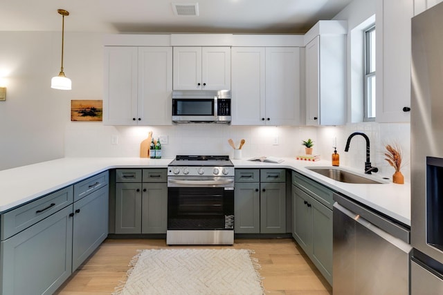 kitchen featuring sink, decorative light fixtures, light hardwood / wood-style flooring, and stainless steel appliances