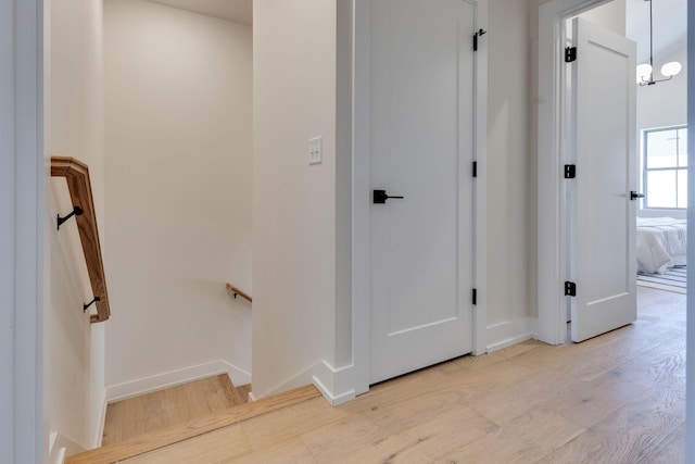 hall with an inviting chandelier and light wood-type flooring