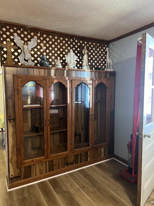 room details featuring wood-type flooring, ornamental molding, and a textured ceiling