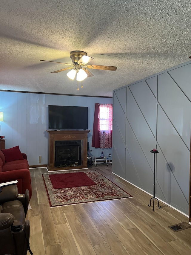 living room with hardwood / wood-style flooring, a textured ceiling, and ceiling fan