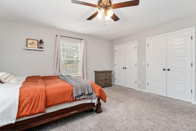 carpeted bedroom featuring multiple closets and ceiling fan