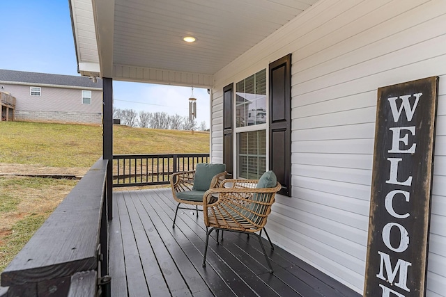 wooden deck with covered porch and a lawn