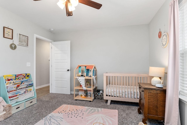 carpeted bedroom featuring a nursery area and ceiling fan