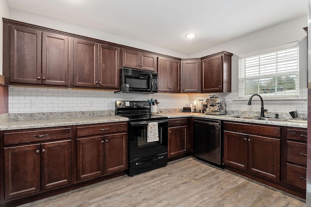 kitchen featuring sink, dark brown cabinetry, black appliances, light hardwood / wood-style floors, and light stone countertops