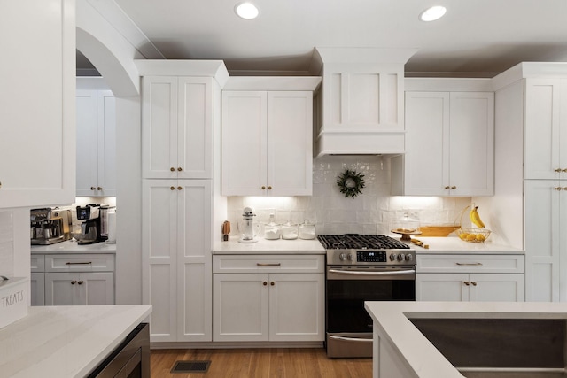 kitchen with white cabinetry, decorative backsplash, stainless steel range with gas cooktop, and light hardwood / wood-style flooring