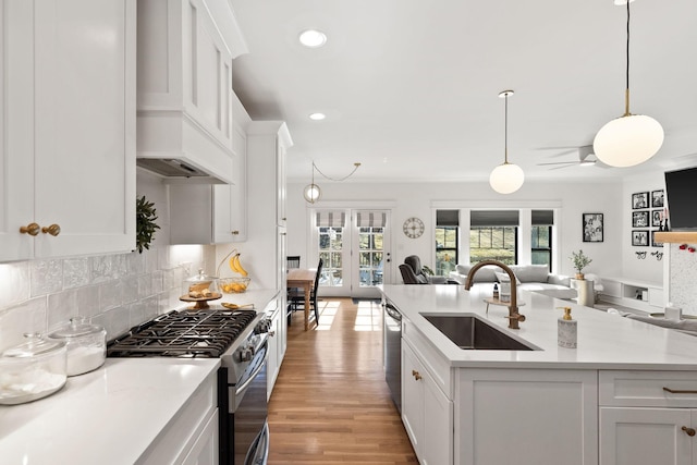 kitchen featuring sink, white cabinetry, light stone counters, decorative light fixtures, and appliances with stainless steel finishes