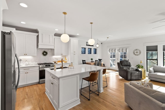 kitchen featuring pendant lighting, white cabinetry, sink, a kitchen island with sink, and stainless steel appliances