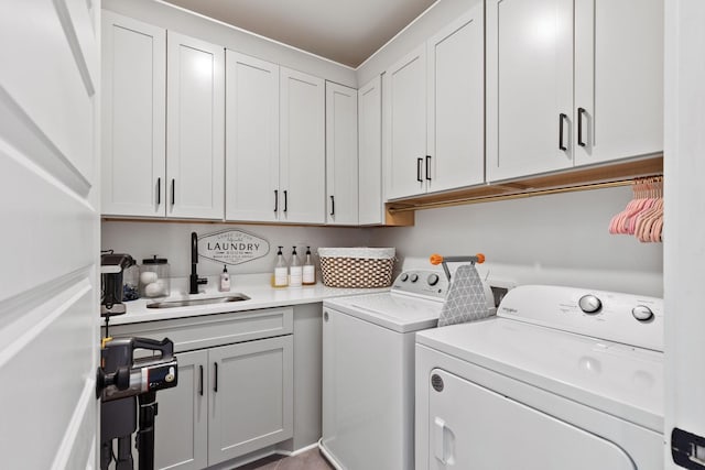 clothes washing area featuring cabinets, sink, and washing machine and dryer