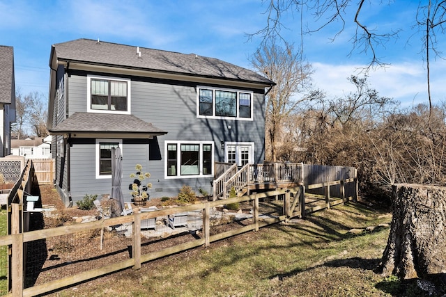 back of property featuring a deck and a lawn